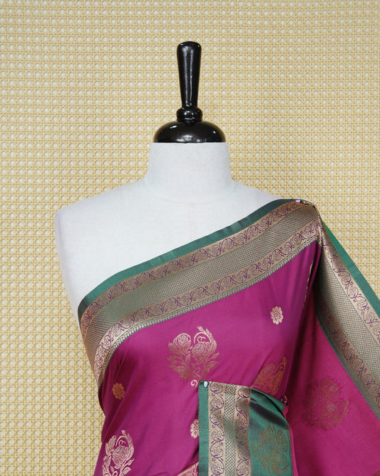 Magenta colour Mulberry silk saree featuring gold floral zari patterns on body, paired with contrast green colour with traditional border, comes with matching blouse piece.