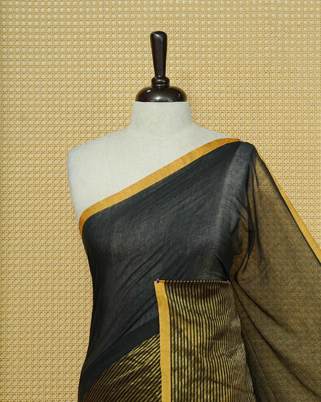 Black Mul Cotton Saree featuring an elegant plain body, beautifully complemented by a gold zari striped border and mustard-yellow tassels.