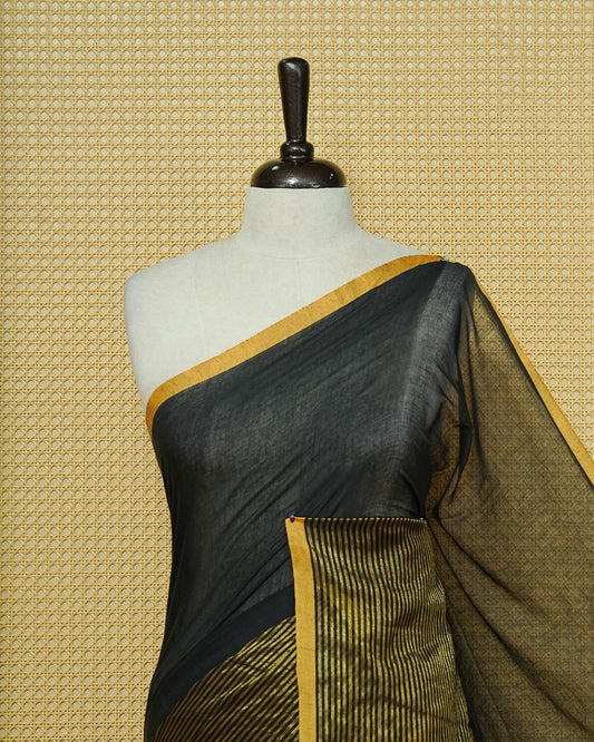Black Mul Cotton Saree featuring an elegant plain body, beautifully complemented by a gold zari striped border and mustard-yellow tassels.