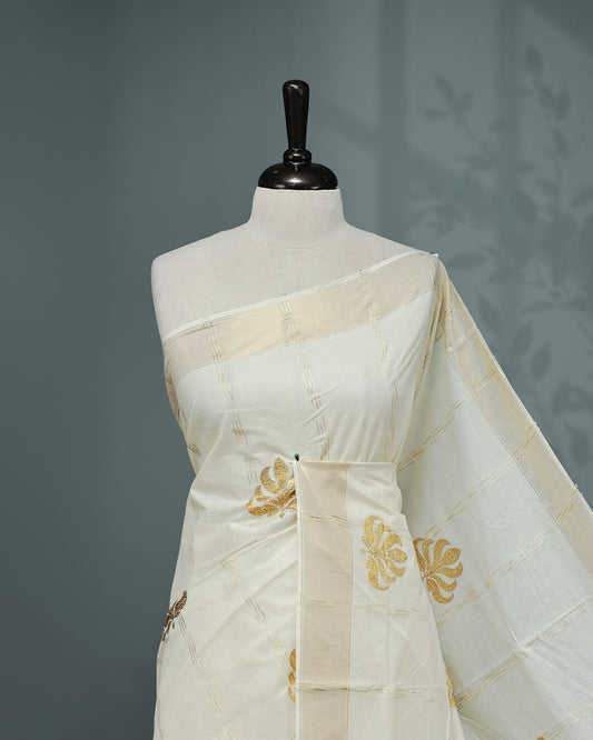 Cream colour Cotton kerala saree featuring Gold Embroidery strips with motifs on the body, complemented by a gold zari Border, paired with a matching blouse piece.