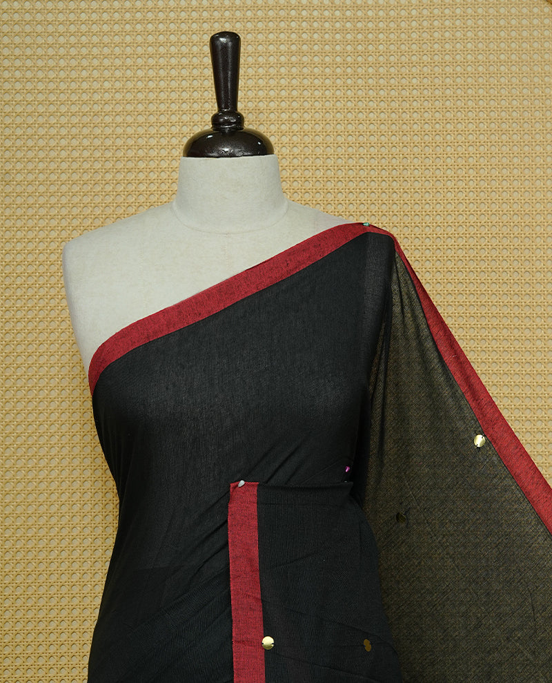 Black colour Mul cotton saree featuring Gold Sequins, complemented by Contrast Red simple Border & tassels.