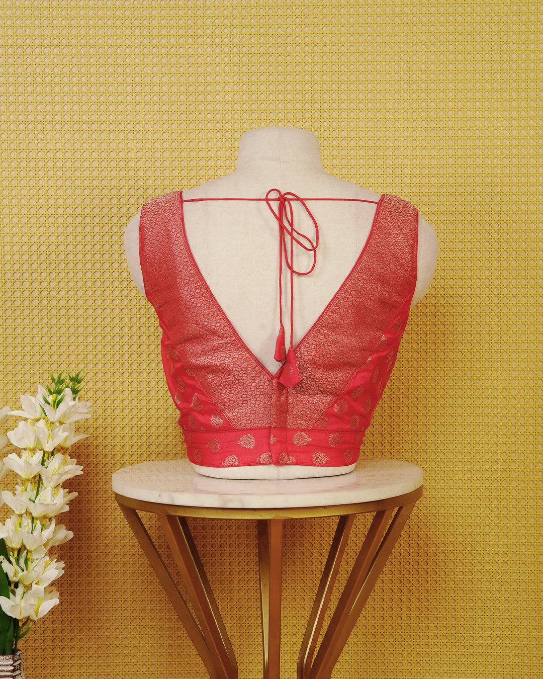 Red colour Sleeveless Blouse Featuring A Stylish V-Neck, Elegant Woven Pattern With Gold Butta Motifs, And A Comfortable Tailored Fit.