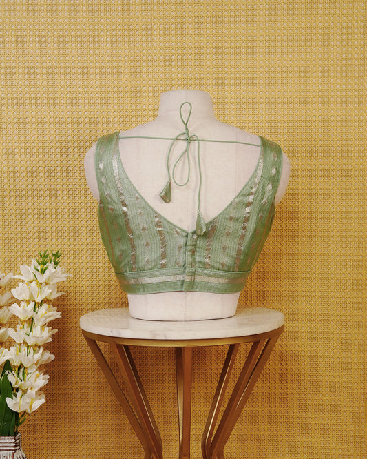 Sage Green colour Sleeveless Blouse Featuring A Stylish V-Neck, Elegant Woven Zari Stripes With Butta Motifs, And A Comfortable Tailored Fit.