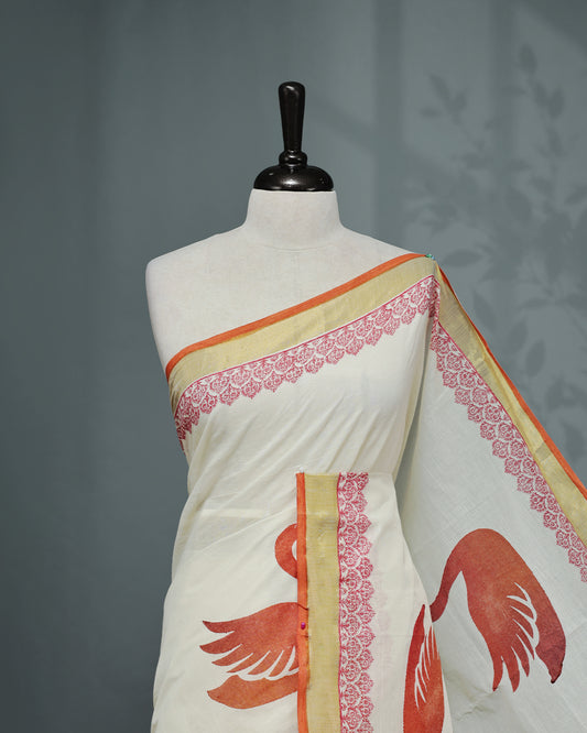 Cream colour Cotton kerala saree featuring Swan Print on the body, complemented by a gold zari with print on Border, paired with a matching blouse piece.