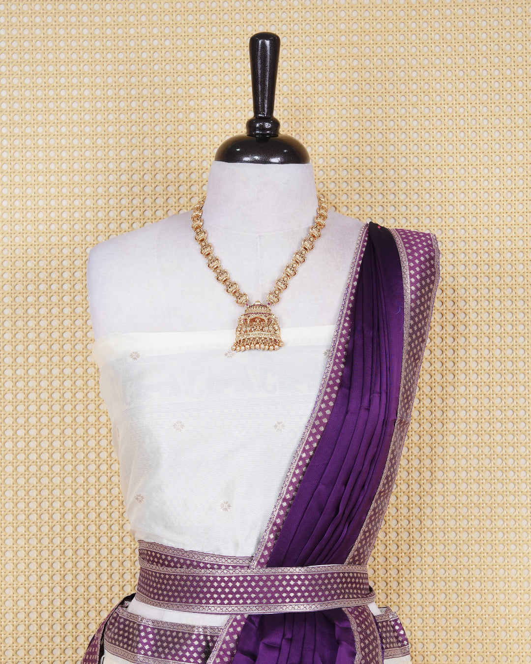 Cream coloured semi silk semi stitched dhavani set featuring gold zari buttas on the body with a contrast purple skirt with a gold zari elephant border, matching blouse piece and dupatta