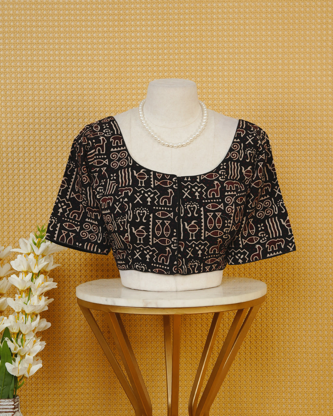 Black Colour Printed Blouse Featuring An All Over Tribal Inspired Geometric Motif Pattern, Enhanced With A Round Neckline, Front Button Closure, And Short Sleeves.