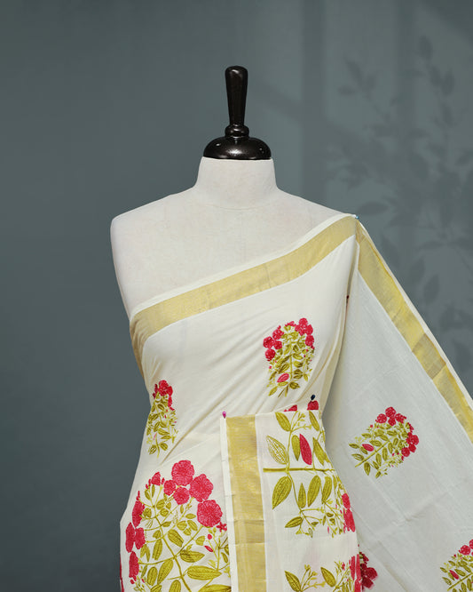 Cream colour Cotton kerala saree featuring Magenta colour floral Print on the body, complemented by a gold zari Border, paired with a matching blouse piece.