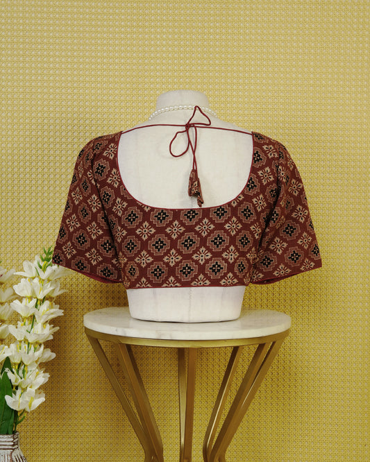 Maroon Colour Printed Blouse Featuring An All Over Geometric Floral Motif, Enhanced With A Round Neckline, Front Button Closure, And Elbow Length Sleeves.