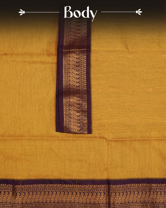 Mustard Yellow  Colour Kalyani cotton saree featuring delicate antique zari floral butta motifs on the body, complemented by a Purple contrast pallu with a rich antique zari peacock border, paired with a matching blouse piece.