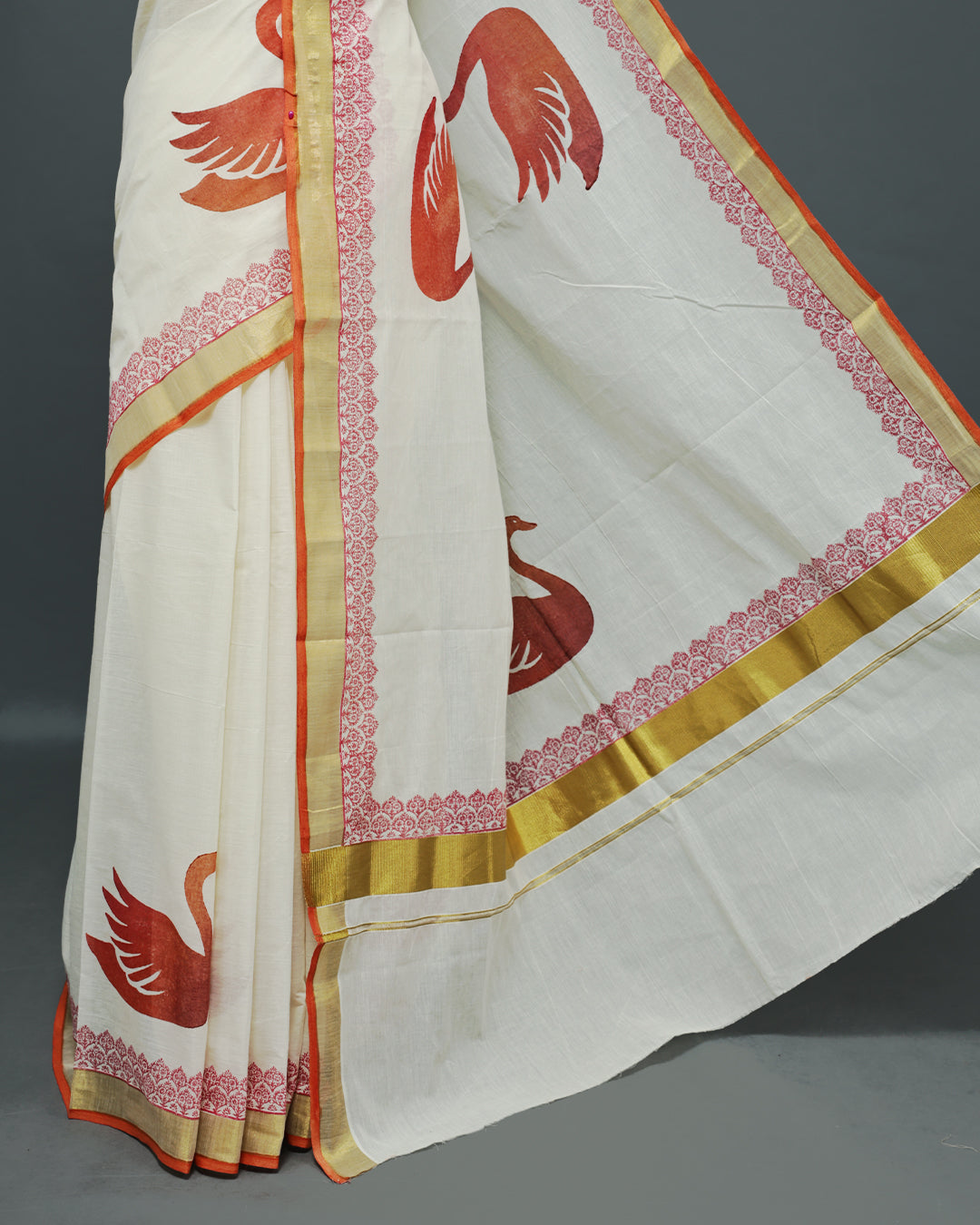 Cream colour Cotton kerala saree featuring Swan Print on the body, complemented by a gold zari with print on Border, paired with a matching blouse piece.