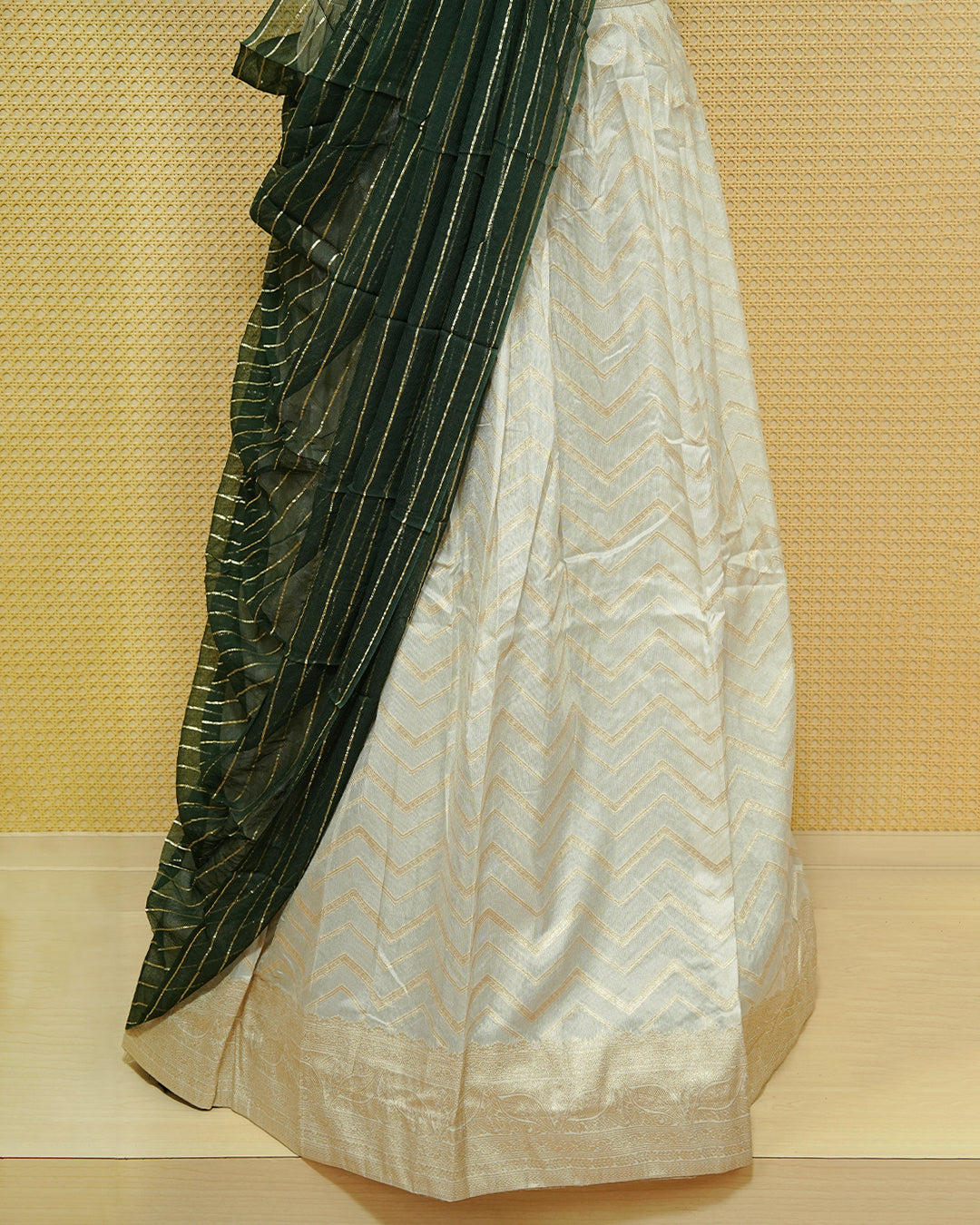 Cream colour Semi Stitched Dhavani set Featuring Gold zari Zigzag pattern With Traditional border skirt, Contrast Green colour Dupatta, Matching blouse piece.