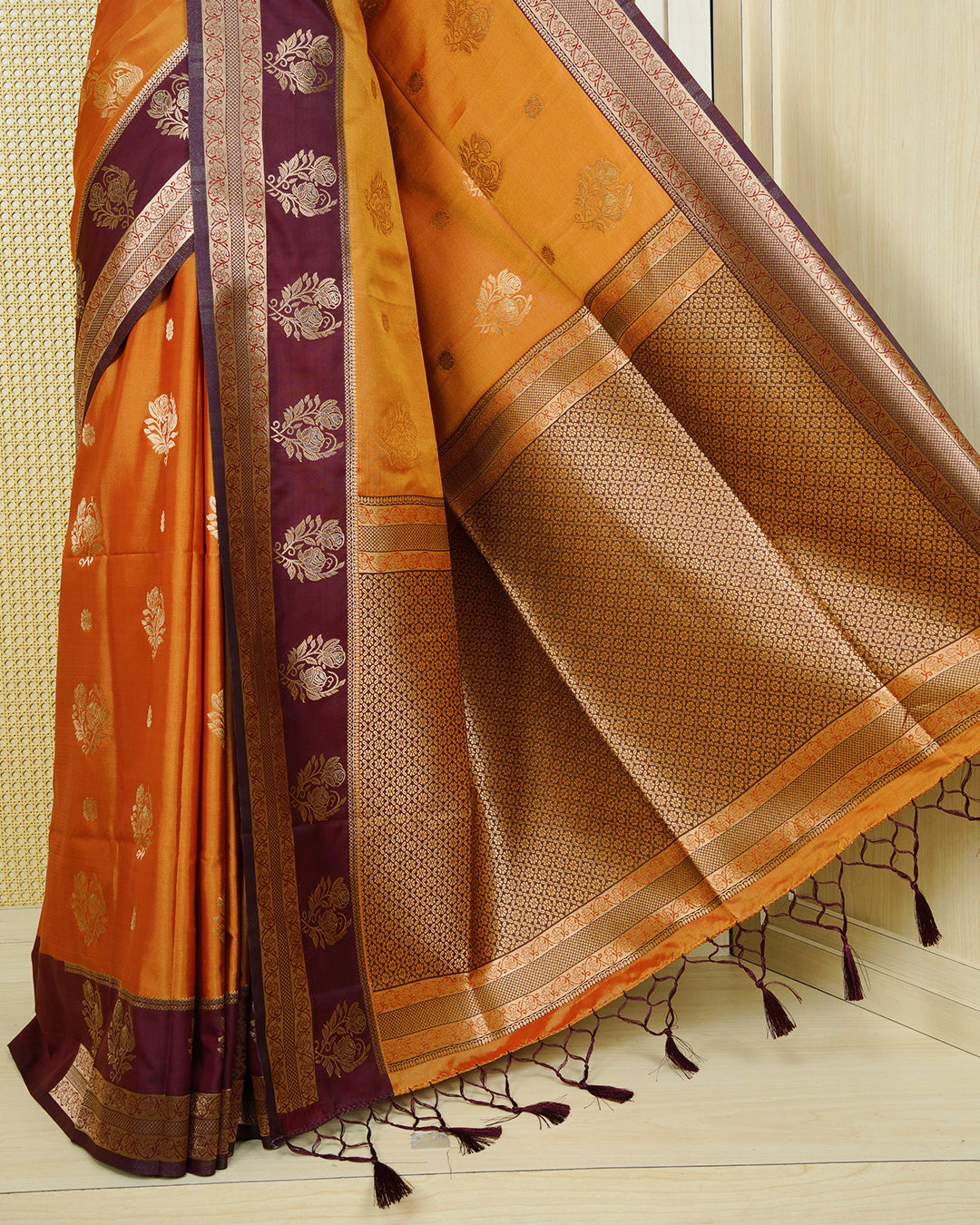 Rust orange colour Mulberry silk saree featuring gold floral zari patterns on body, paired with contrast maroon colour with traditional border, comes with matching blouse piece.