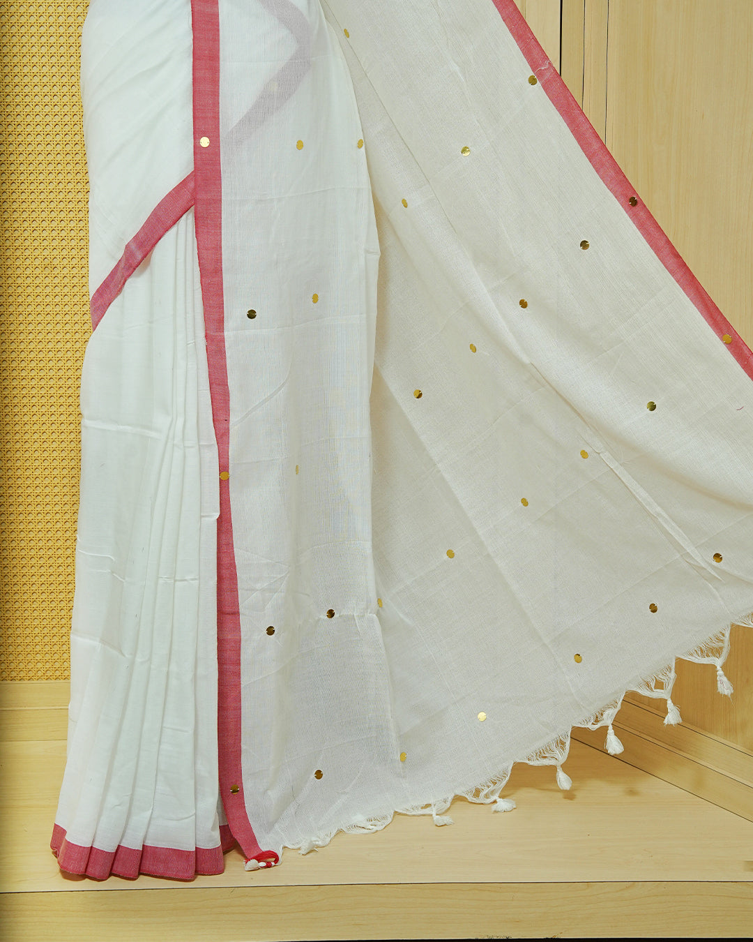 White colour Mul cotton saree featuring Gold Sequins, complemented by Contrast Red simple Border & tassels.
