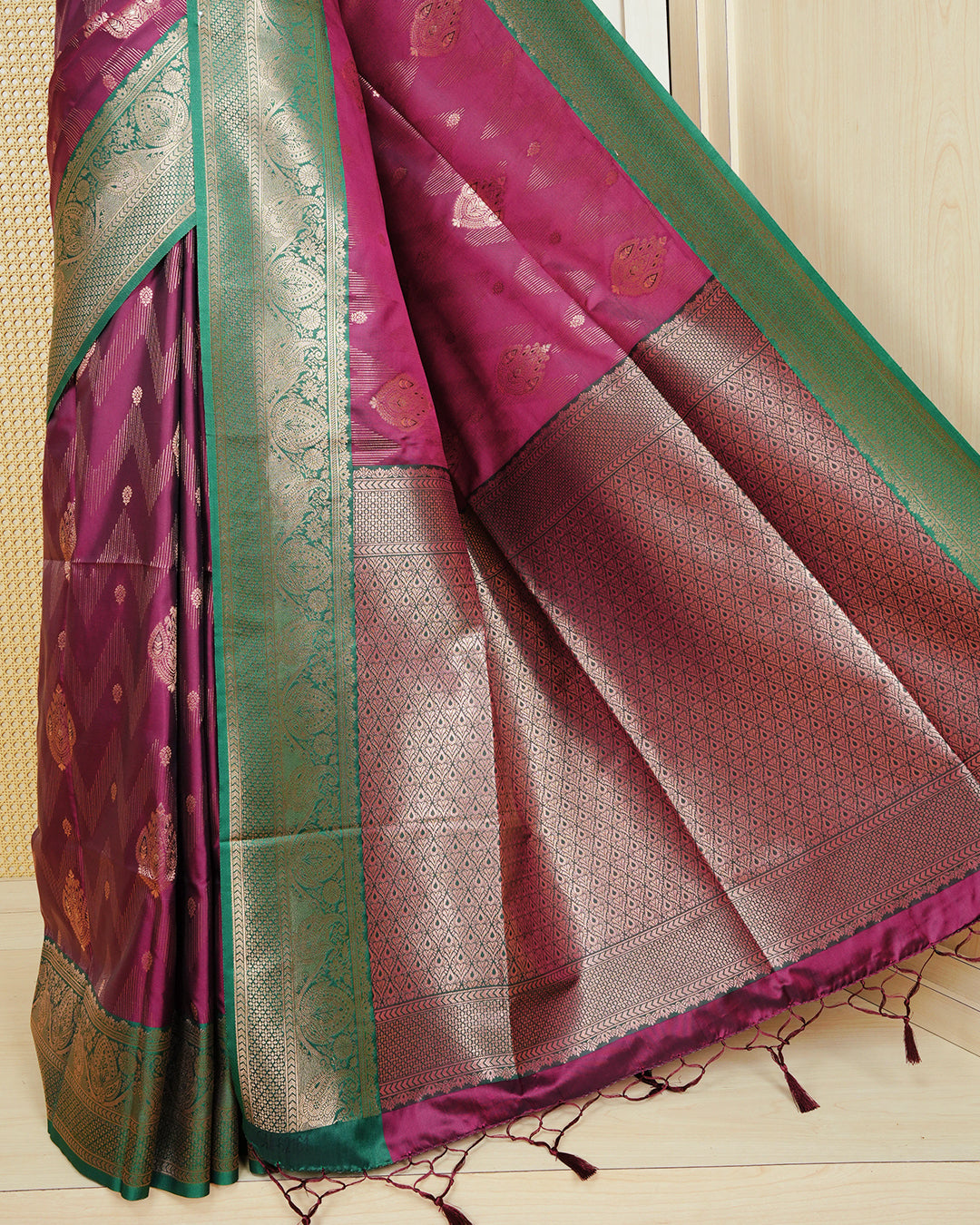 Maroon colour Mulberry silk saree featuring gold floral zari patterns on body, paired with contrast green colour with traditional border, comes with matching blouse piece.