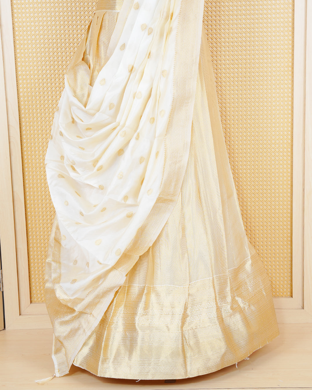 Cream coloured tissue semi stitched dhavani set featuring gold zari Motifs on the body with a matching gold zari bordered skirt & blouse piece and dupatta.