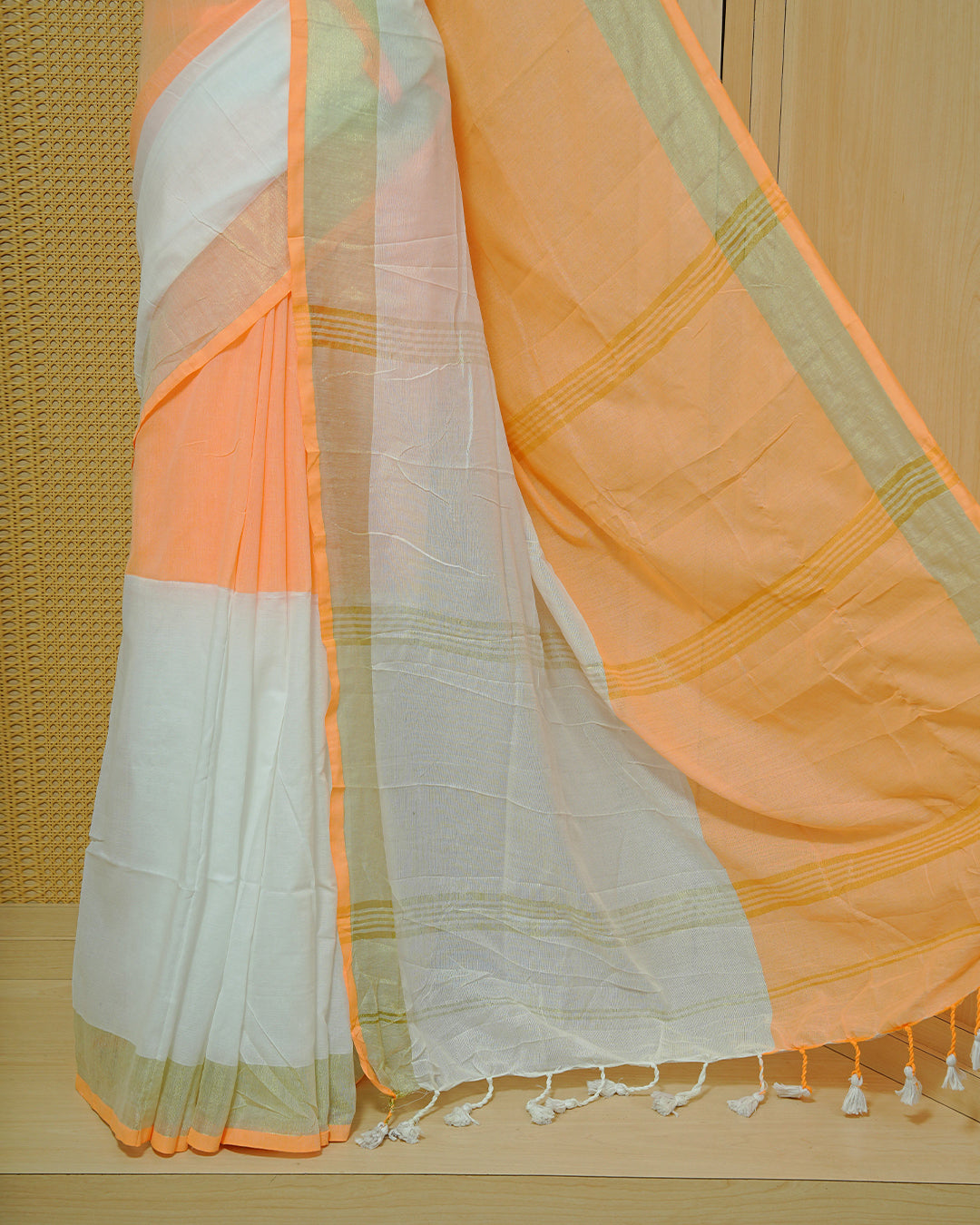Orange & White Colour Mul Cotton Saree featuring a soft dual-tone body with a subtle golden zari border, elegant striped zari detailing on the pallu, and white tassels.