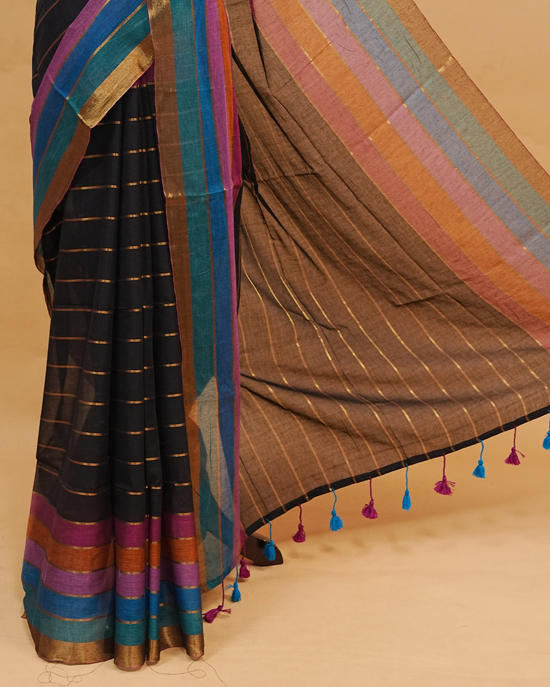 Black colour  mul cotton saree featuring a striped body, vibrant multicolour border, and striped pallu. Comes without a blouse piece.