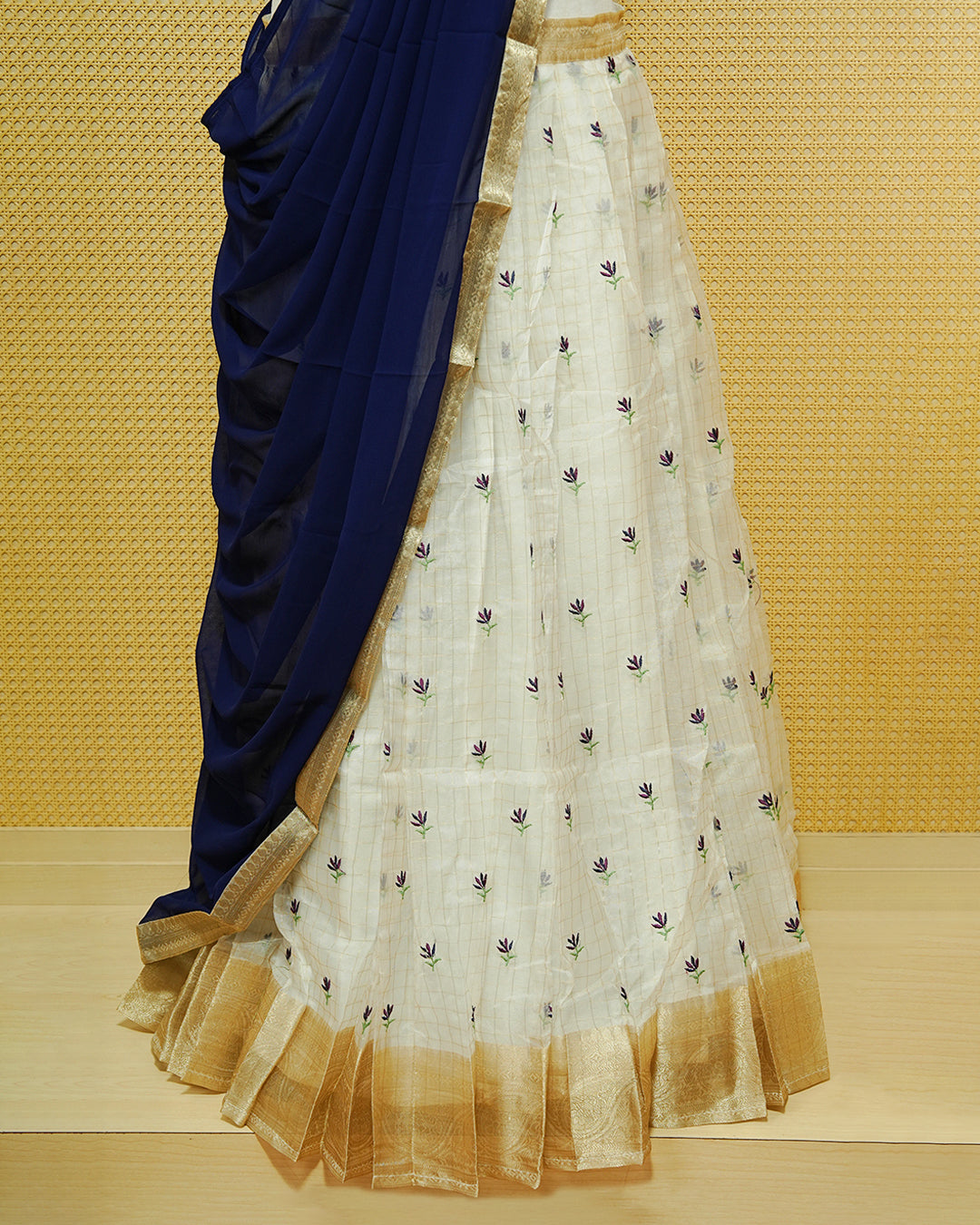 Cream colour Semi stitched Dhavani set featuring Gold zari checked pattern with floral motifs on skirt with traditional border, comes with contrast Colour Dupatta & matching blouse piece.