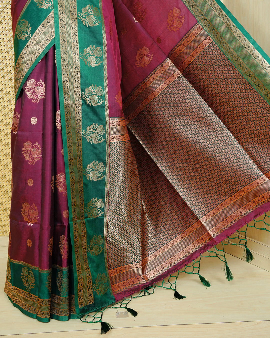 Maroon colour Mulberry silk saree featuring gold floral zari patterns on body, paired with contrast green colour with traditional border, comes with matching blouse piece.
