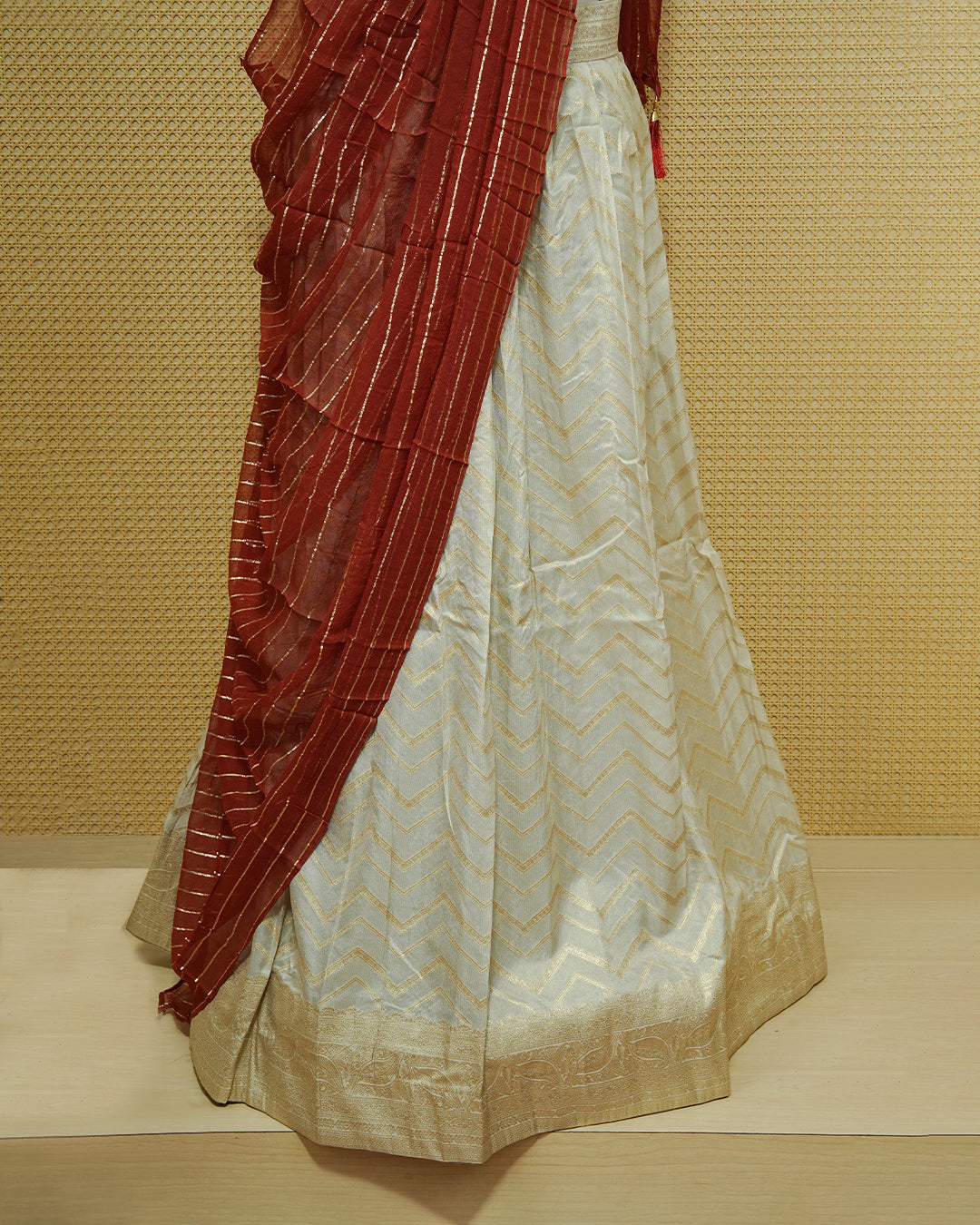 Cream colour Semi Stitched Dhavani set Featuring Gold zari Zigzag pattern With Traditional border skirt, Contrast Red colour Dupatta, Matching blouse piece.
