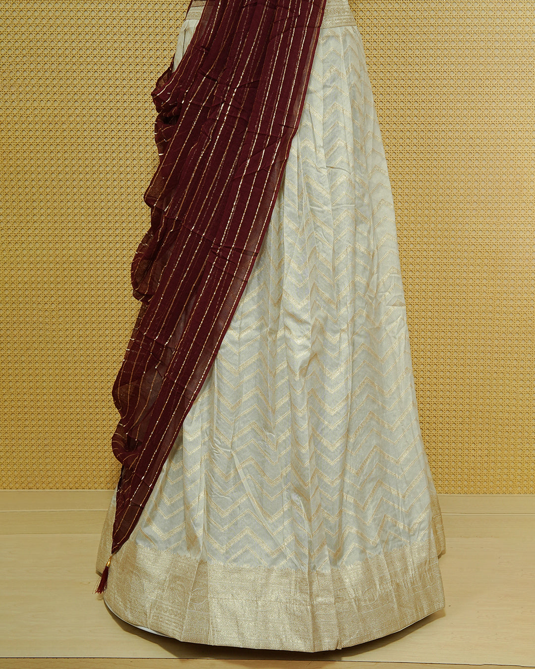 Cream colour Semi Stitched Dhavani set Featuring Gold zari Zigzag pattern With Traditional border skirt, Contrast Maroon colour Dupatta, Matching blouse piece.