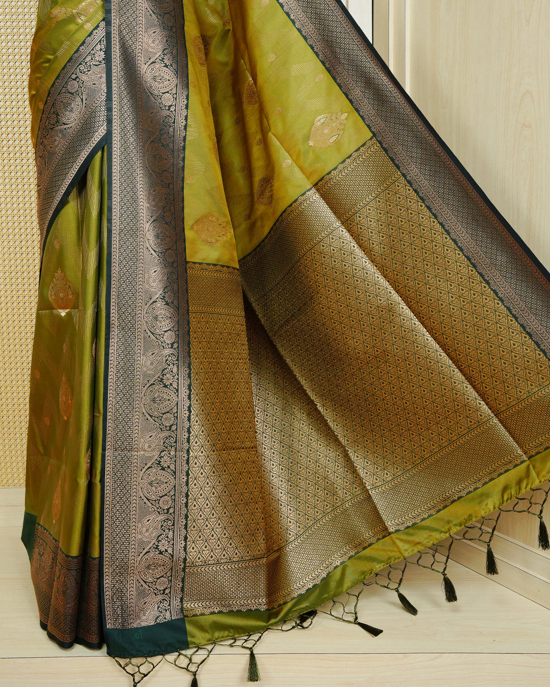 Olive colour Mulberry silk saree featuring floral gold zari patterns on body, paired with contrast bottle green colour with traditional border, comes with matching blouse piece.