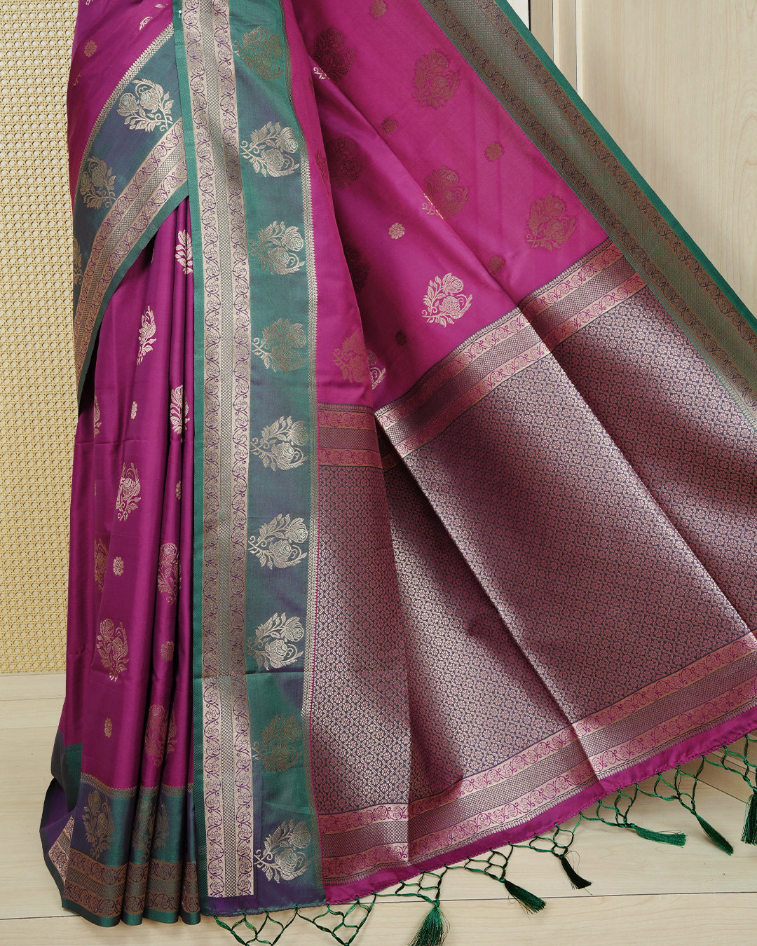 Magenta colour Mulberry silk saree featuring gold floral zari patterns on body, paired with contrast green colour with traditional border, comes with matching blouse piece.