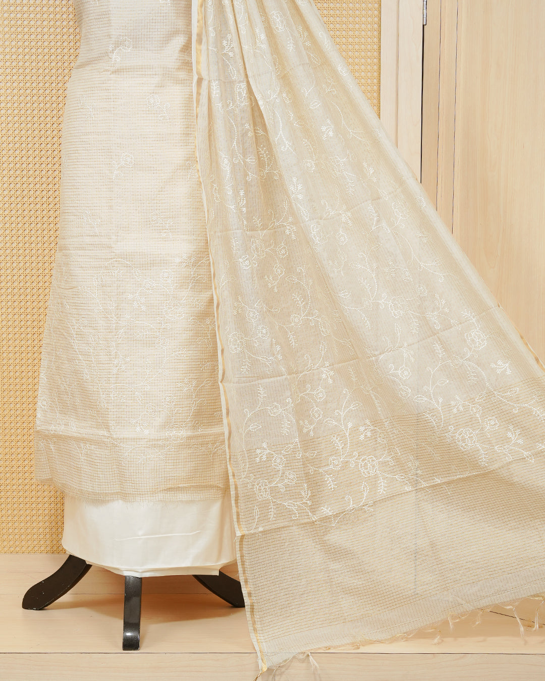 Cream colour tissue salwar material featuring gold zari checked pattern with elegant floral threadwork pattern on the body, paired with a matching bottom and an elegant dupatta.