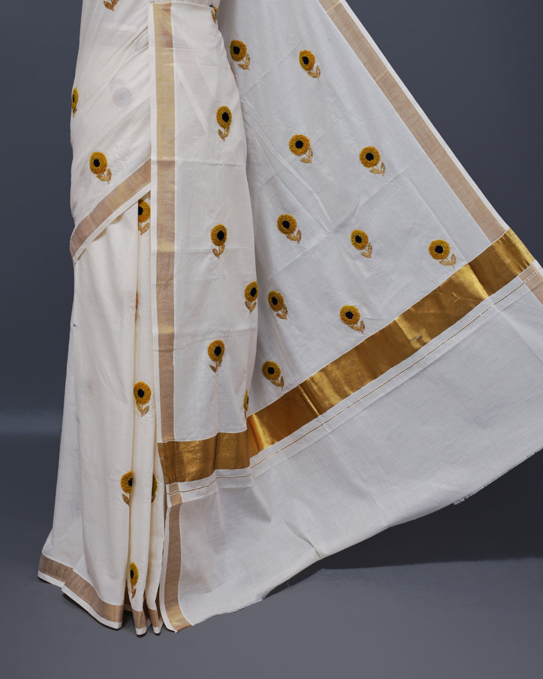 Cream colour Cotton kerala saree featuring Sunflower Embroidery work on the body, complemented by a gold zari Border, paired with a matching blouse piece.
