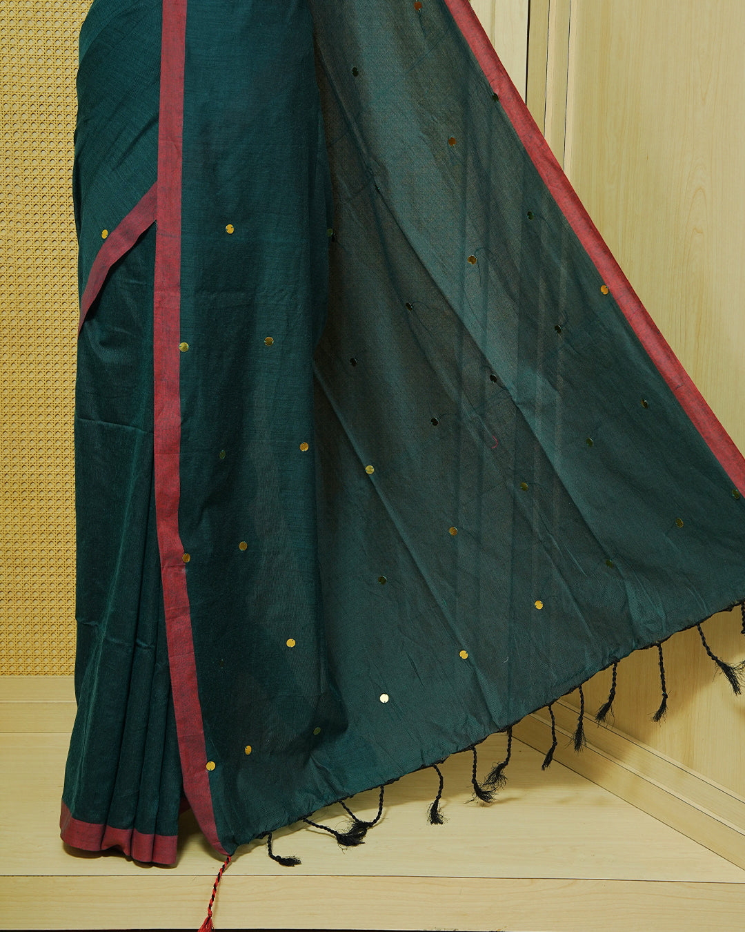 Dark Green Colour Mul Cotton Saree featuring delicate gold sequin detailing on the body, a contrasting maroon border, finished with black tassels.