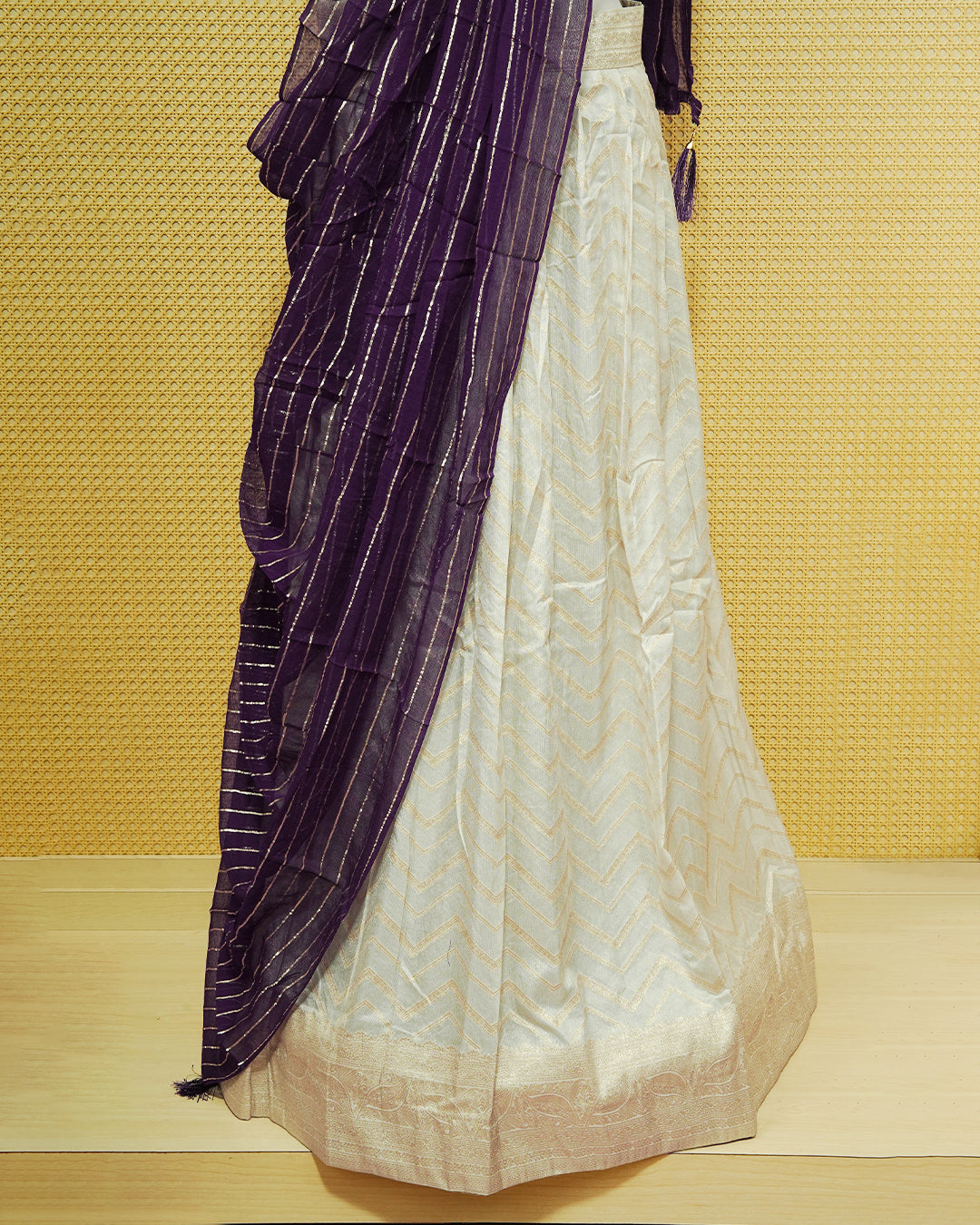 Cream colour Semi Stitched Dhavani set Featuring Gold zari Zigzag pattern With Traditional border skirt, Contrast Purple colour Dupatta, Matching blouse piece.