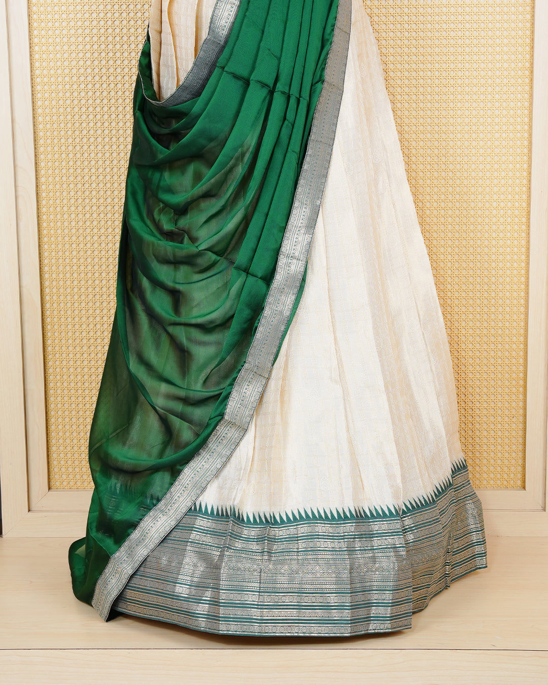 Cream colour Tissue Semi stitched dhavani set featuring Gold zari check pattern on body ,contrast Green colour with gold zari bordered skirt, paired with matching blouse piece & dupatta.