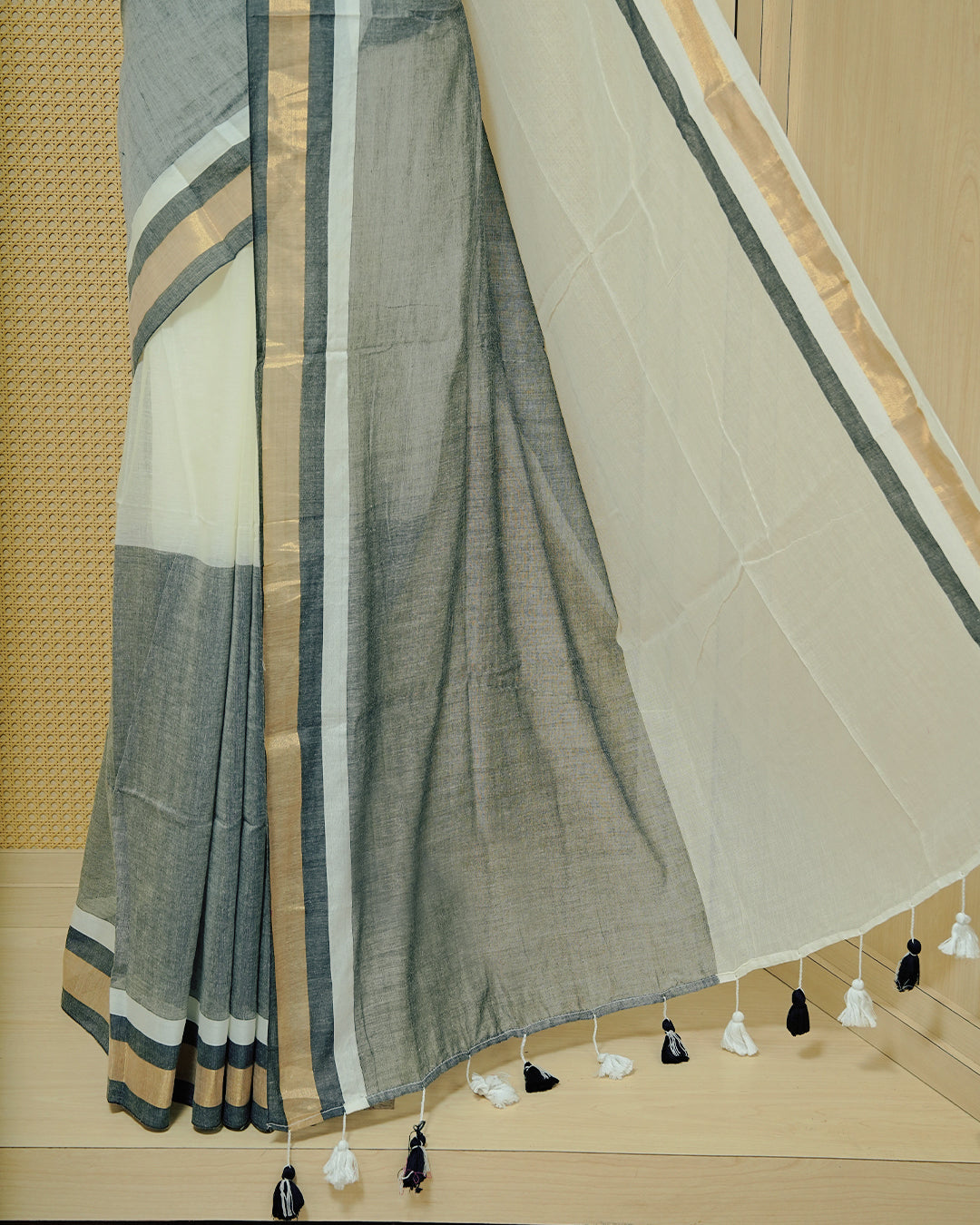 White  Colour Mul Cotton Saree featuring a grey and gold zari border with a matching grey pallu, finished with black and white tassels.