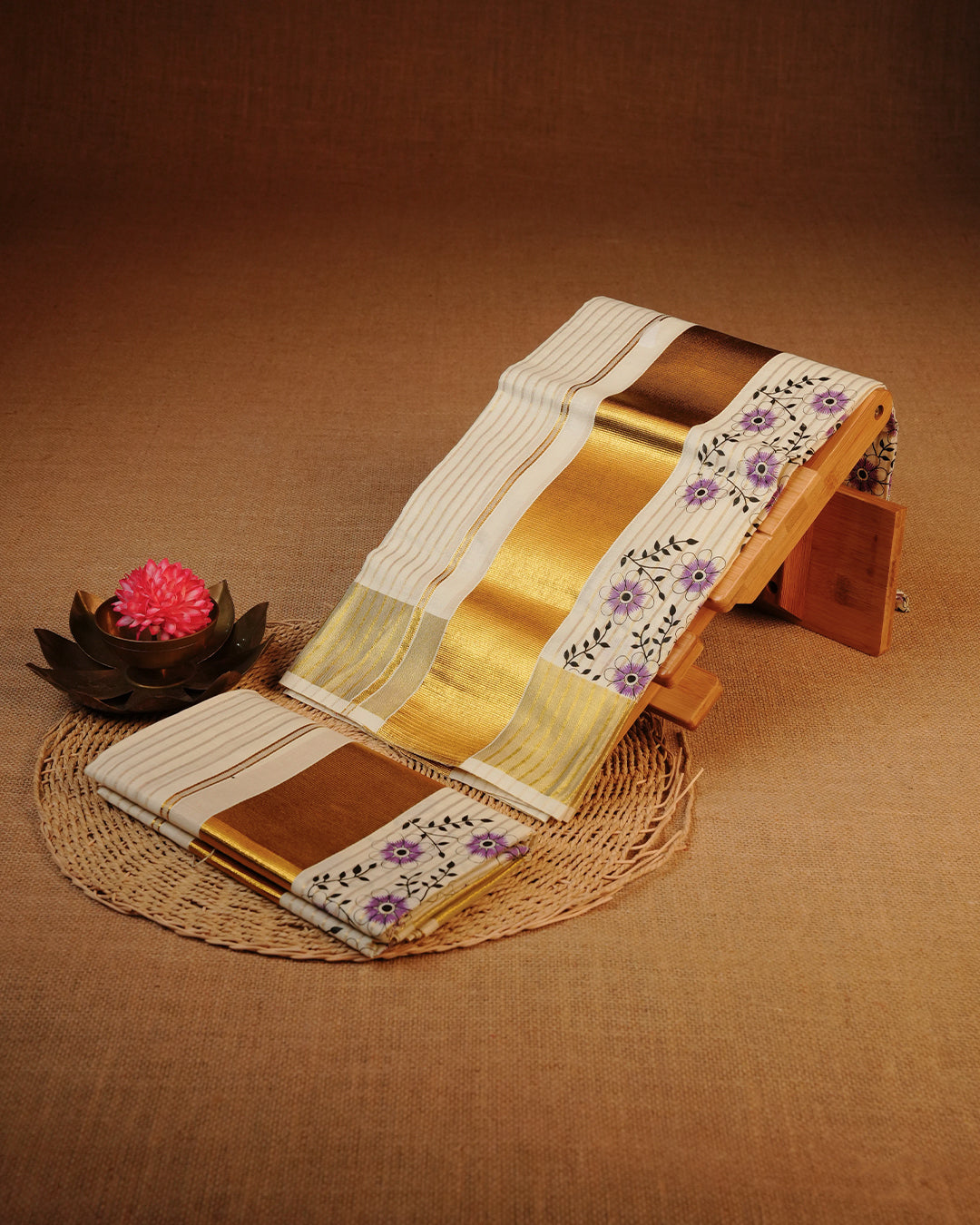 Cream colour cotton Set Mundu With Gold Zari stripes on body, enhanced with gold Kasav With Purple Floral Printed kara.