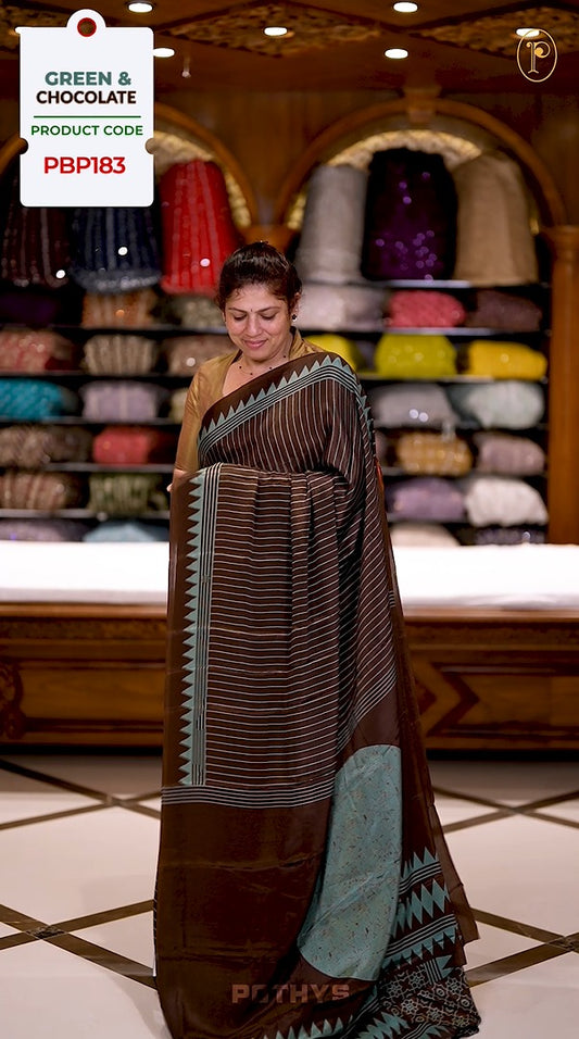 Green and Chocolate colour semi modal saree featuring a vertical line prints, accented with a contrasting temple border and a bold circular motif on the pallu, paired with a matching printed blouse.