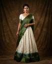 Off White colour half saree material featuring delicate zari buttas on the blouse and skirt, paired with a contrast Green zari border and matching small zari motifs dupatta