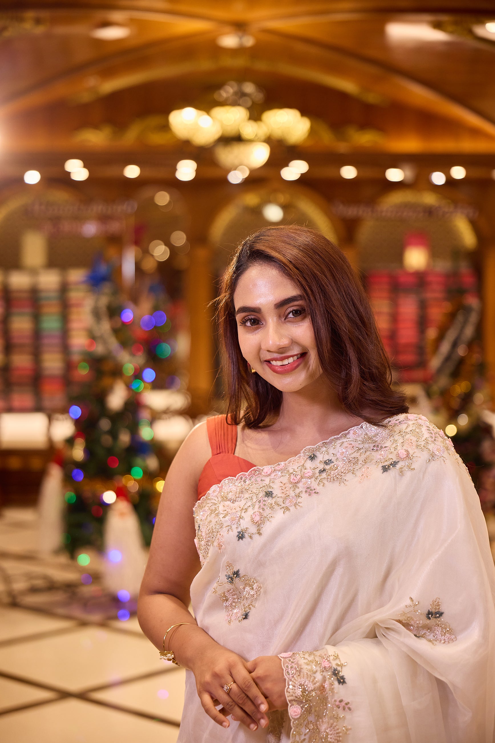 White colour Pure Organza designer saree featuring soft pastel pink and blue floral bead and sequin embroidery with a delicately scalloped embellished border, paired with a matching designer blouse.