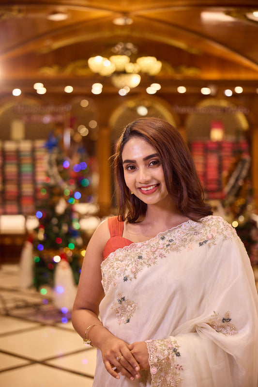 White colour Pure Organza designer saree featuring soft pastel pink and blue floral bead and sequin embroidery with a delicately scalloped embellished border, paired with a matching designer blouse.