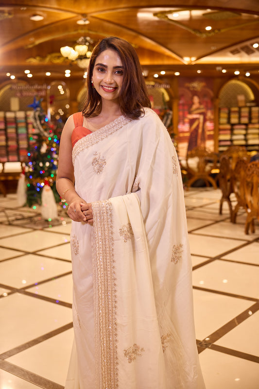 Cream colour pure organza saree with elegant hand embroidery featuring beads, sequins, pearls and thread detailing all over the body, finished with a beautifully crafted scallop border, paired with a matching worked blouse.