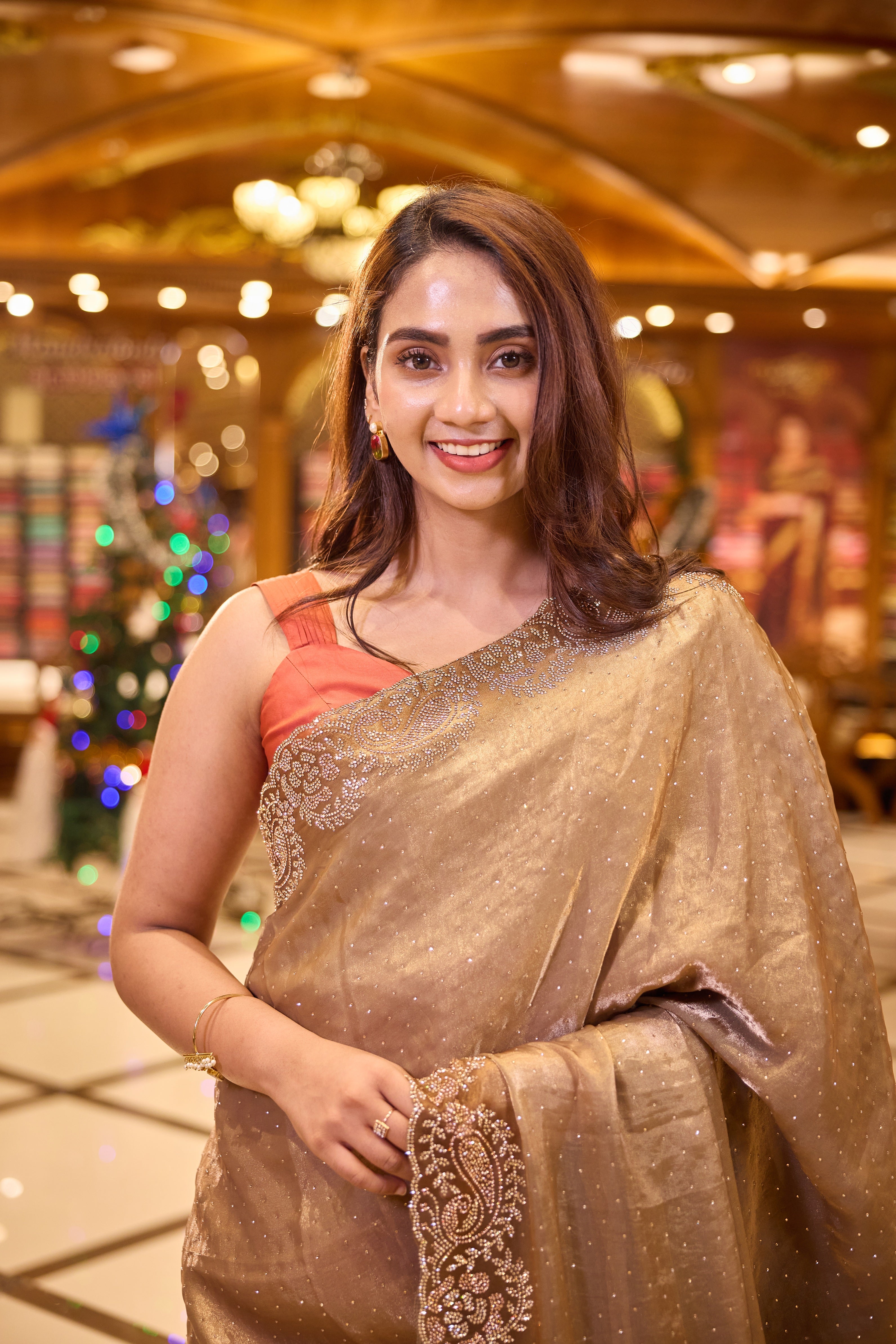 Rich antique gold colour Shimmer tissue coated saree, adorned with Swarovski crystal work and finished with a beautiful contrast scallop border, paired with a matching worked blouse