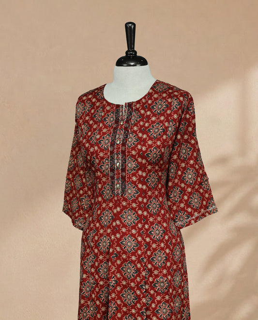 Brick Red Colour Kurti featuring digital floral prints on the body, a round neckline with embroidered detailing, and 3/4 sleeves Design.