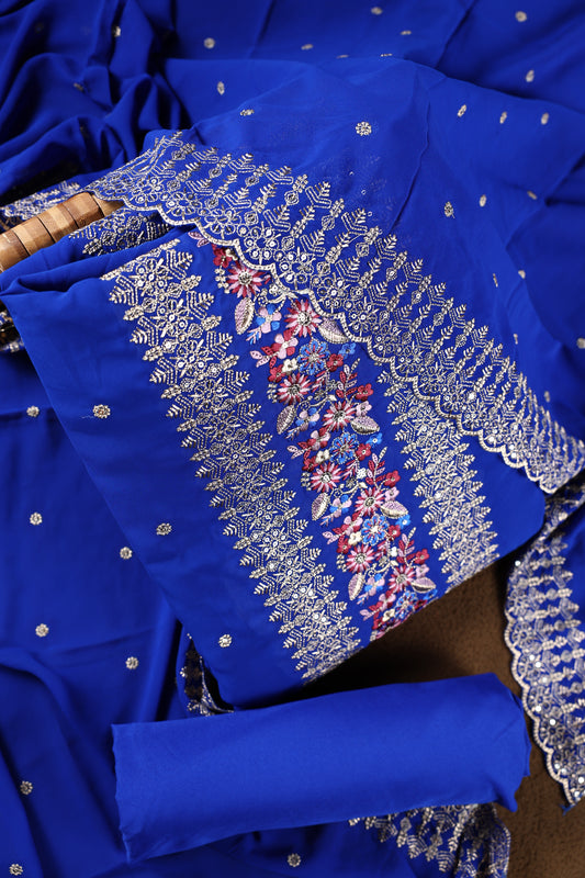 Royal blue colour churidhar material beautifully designed with golden floral embroidery and multicolour thread highlights, paired with a plain matching bottom and an elegant embroidered dupatta.