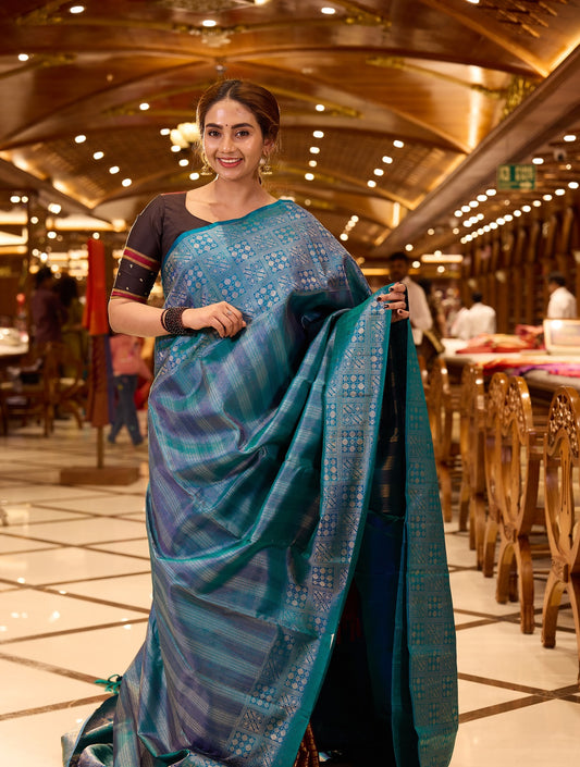 Peacock Blue Samudrika Pattu saree adorned with elegant multi-zari geometric vertical brocade weaving, highlighted by a traditional turning border with intricate box patterns, and paired with a matching blouse piece.