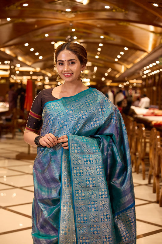 Peacock Blue Samudrika Pattu saree adorned with elegant multi-zari geometric vertical brocade weaving, highlighted by a traditional turning border with intricate box patterns, and paired with a matching blouse piece.