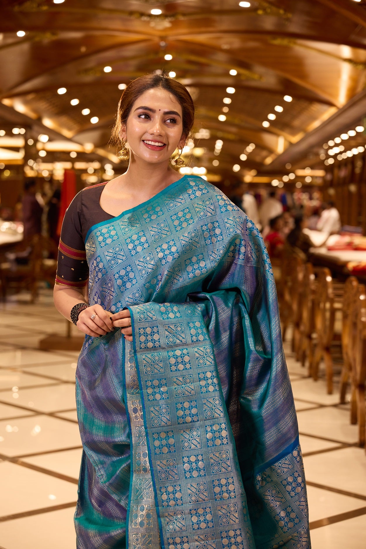 Peacock Blue Samudrika Pattu saree adorned with elegant multi-zari geometric vertical brocade weaving, highlighted by a traditional turning border with intricate box patterns, and paired with a matching blouse piece.