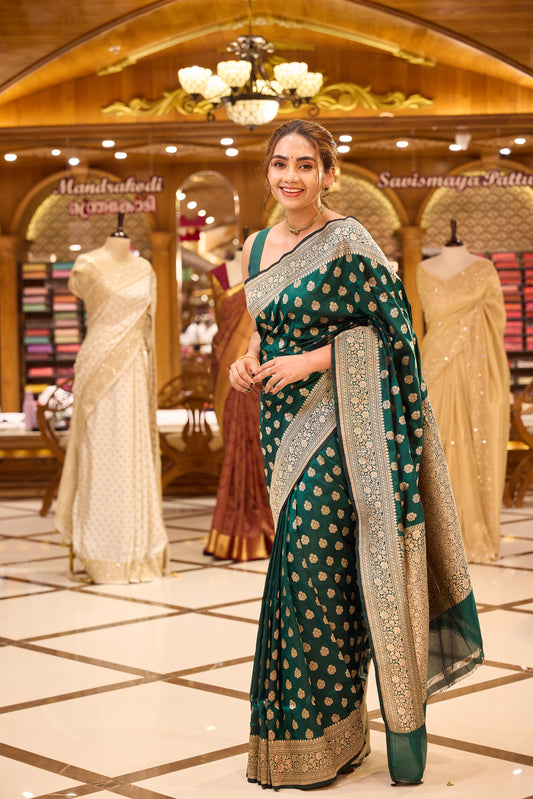 Ruby green colour pure Banaras Katan saree adorned with small motifs all over the body, featuring a traditional Banaras border and pallu, paired with a matching blouse.