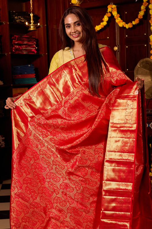 Rich red pure Kancheepuram silk saree featuring intricate gold zari weaving, a lustrous gold zari pallu, and a broad gold zari border, beautifully paired with matching blouse.
