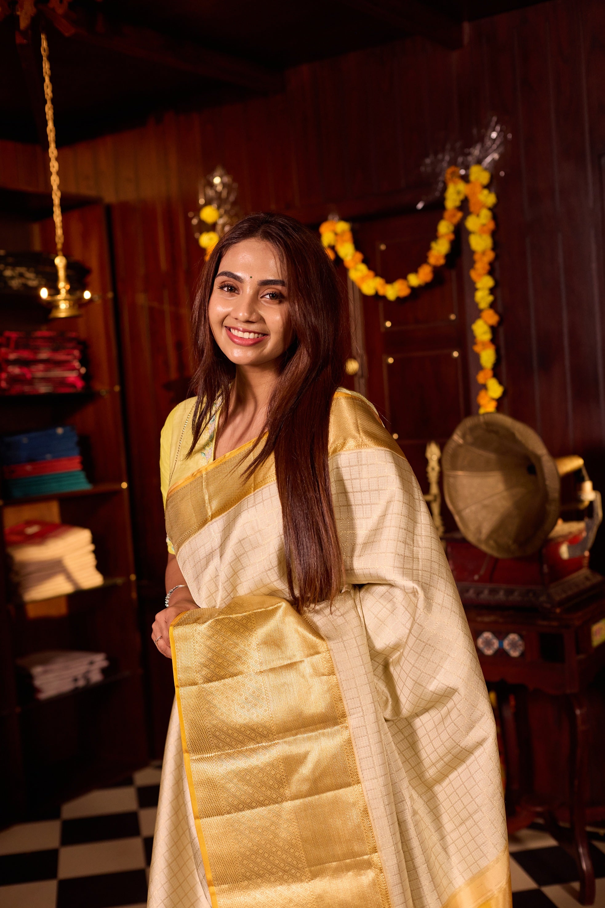 Ivory colour pure Kancheepuram silk saree featuring subtle self check weaving, a rich gold zari pallu, and a broad gold zari border, elegantly paired with a matching blouse.