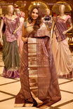 Elegant wine brown colour Kancheepuram silk saree adorned with an all over rich geometric zari weave, beautifully complemented by a broad traditional gold zari border and paired with a matching blouse piece