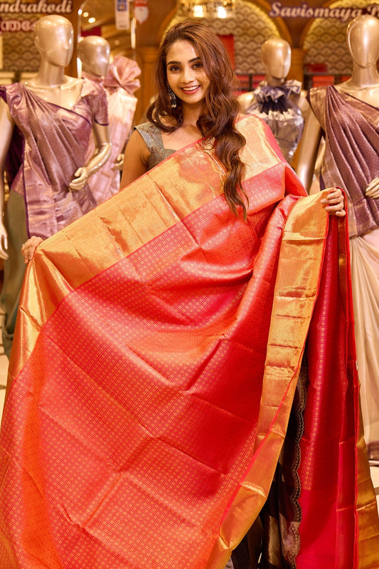 Graceful salmon pink colour Kancheepuram Samudrika Pattu Saree adorned with exclusive floral kolam concept jacquard and detailed Meenakari weaving, complemented by a classic traditional pure zari border and a matching blouse piece.